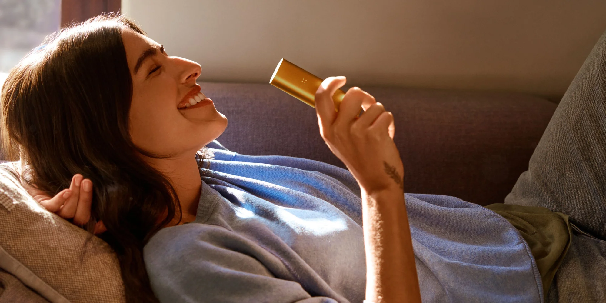 Woman relaxing on a couch enjoying a PAX vaporizer