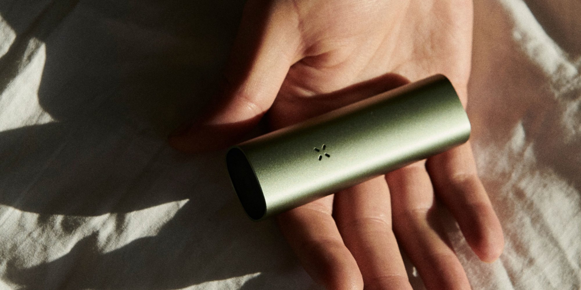 A hand holding a PAX vaporizer