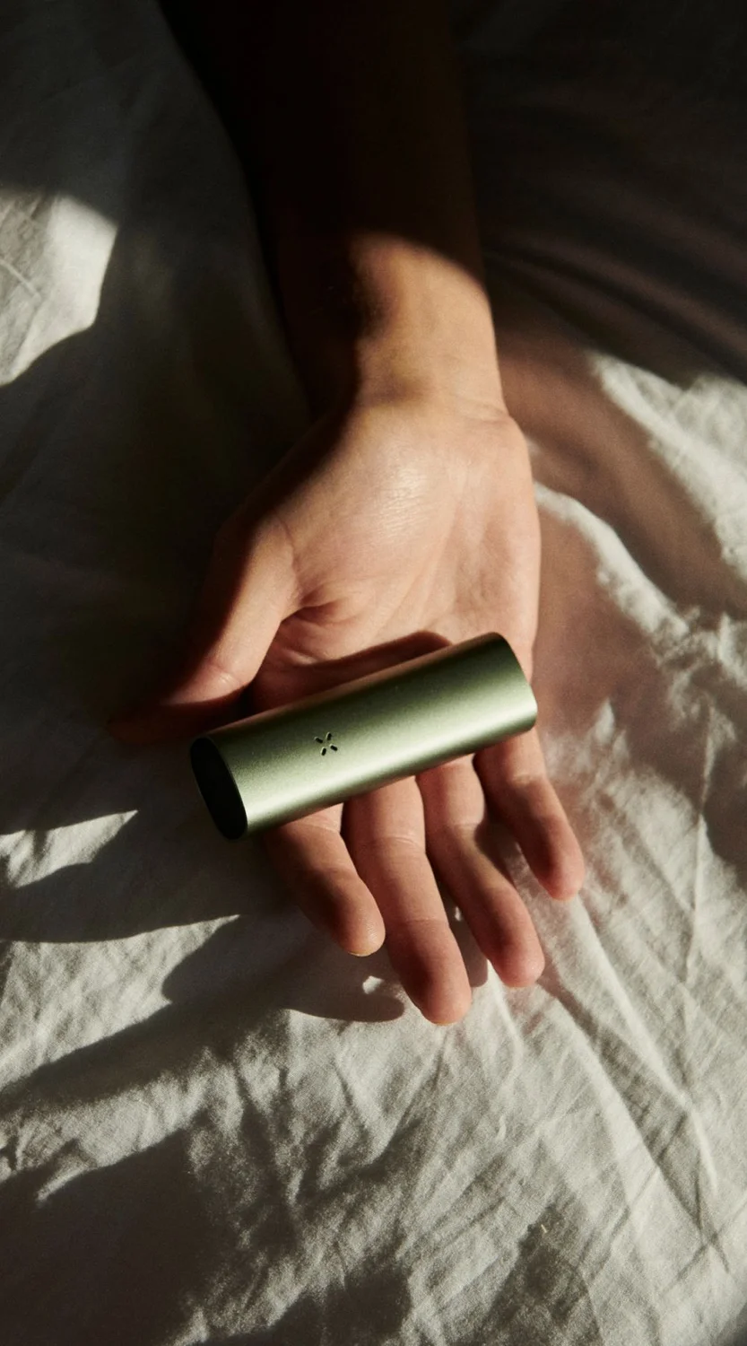 A hand holding a PAX vaporizer