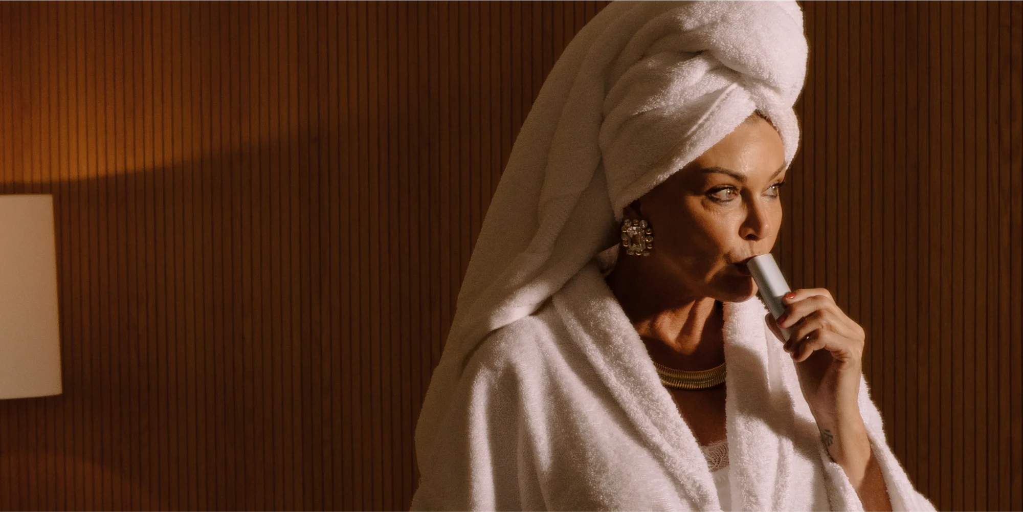 Woman wrapped in towels using a PAX dry herb and concentrate vaporizer