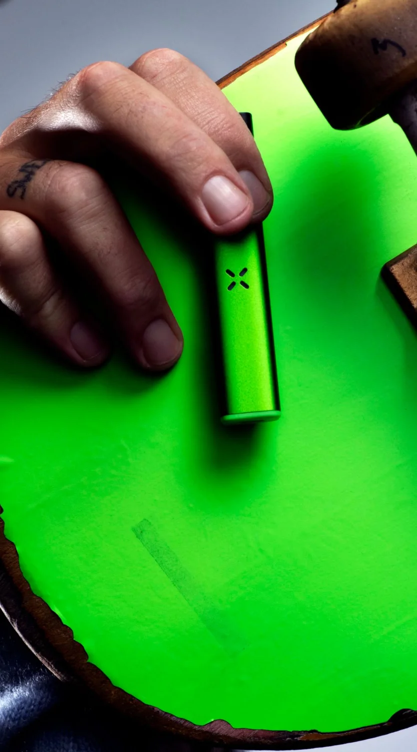 Holding a green skateboard with a pax era vaporizer