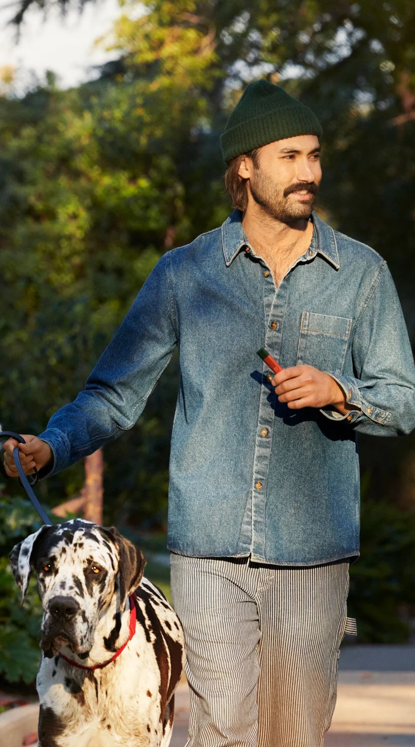 A guy with a beanie and mustache out walking his Dalmatian using a Pax Era