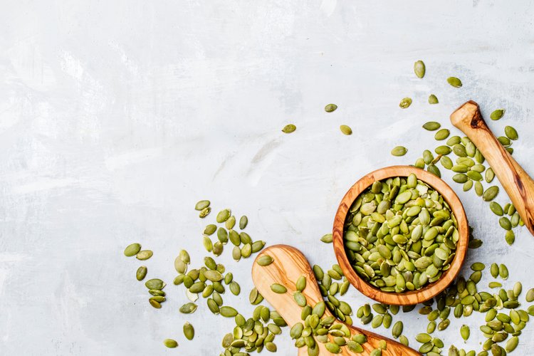 Pumpkin seeds spread out in a wooden bowl