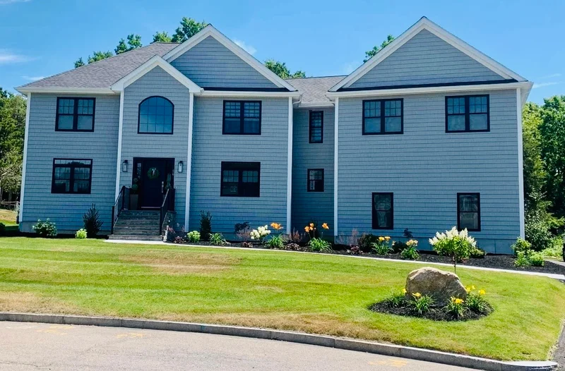 Completed gray-sided custom home with a landscaped lawn