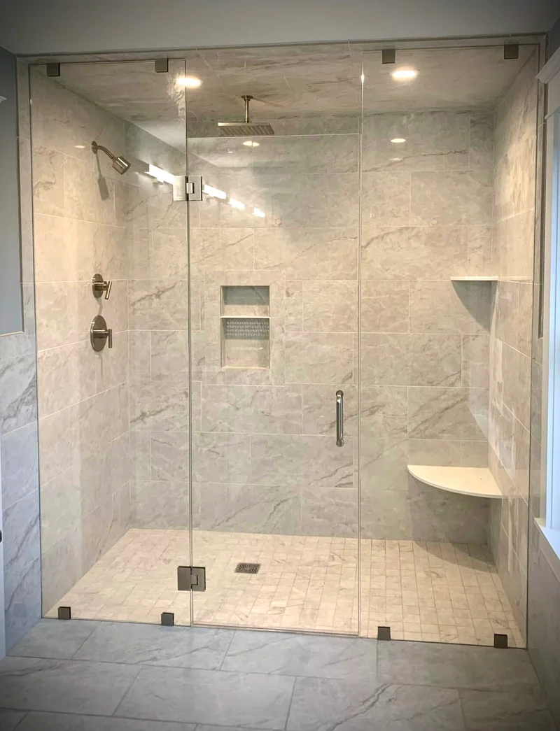 Frameless glass shower with marble-look tile and built-in bench seating