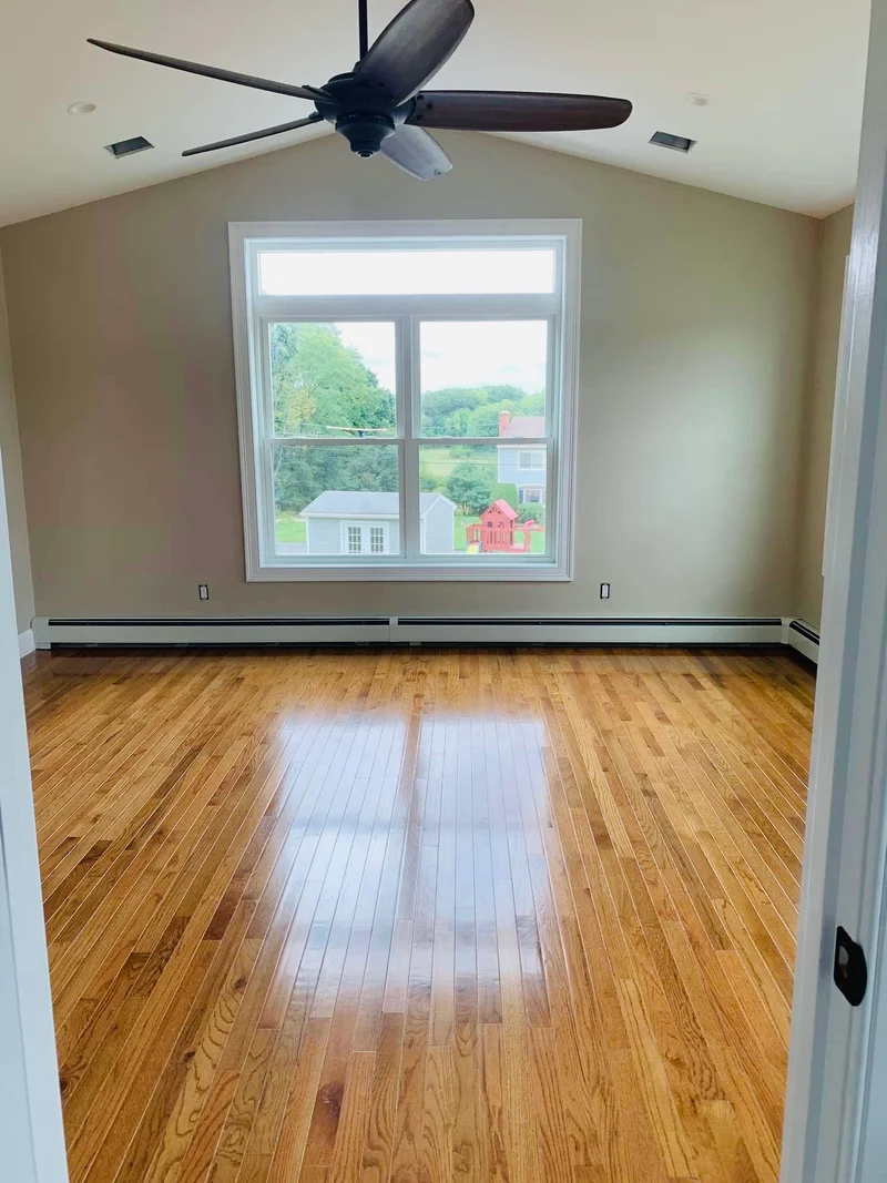 Finished addition living space with hardwood floors and large windows