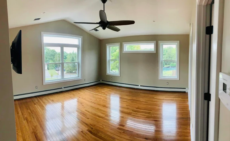 Finished addition living room with hardwood floors and multiple windows
