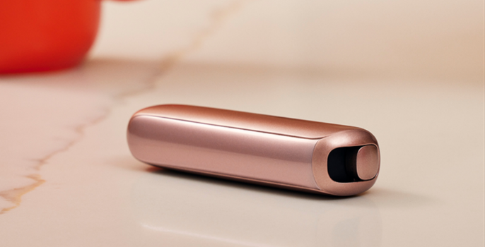 The Ploom AURA Rose Gold device placed on a table.