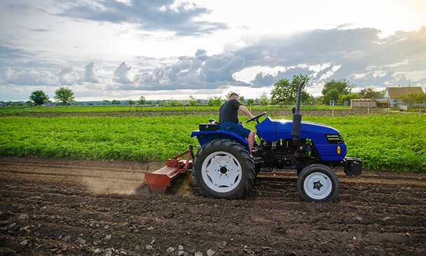 A farmer on a tractor mills and cultivates an agricultural field