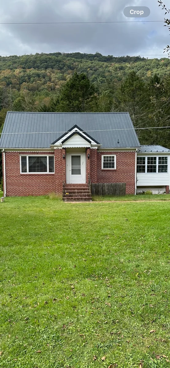 Before — Brick home with a gray metal roof before and a red coated roof after