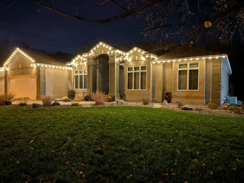 Large home with festive roofline lighting and a glowing holiday entry