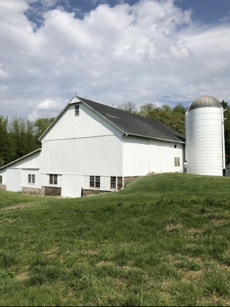 After — Weathered barn and silo before and freshly painted white exterior after restoration