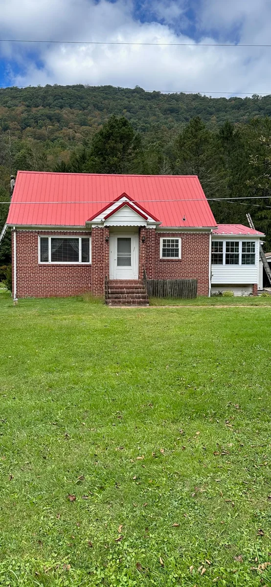 After — Brick home with a gray metal roof before and a red coated roof after