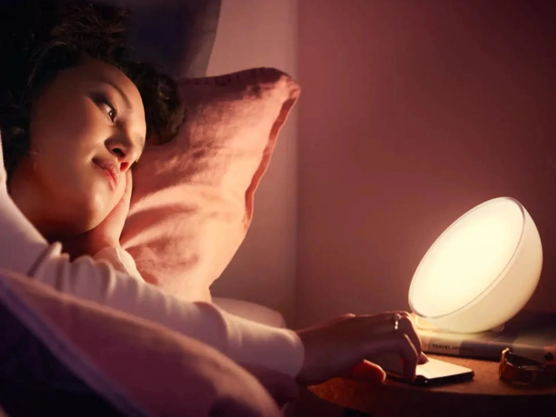 Frau liegt im Bett neben Smart Home Nachttischlampe