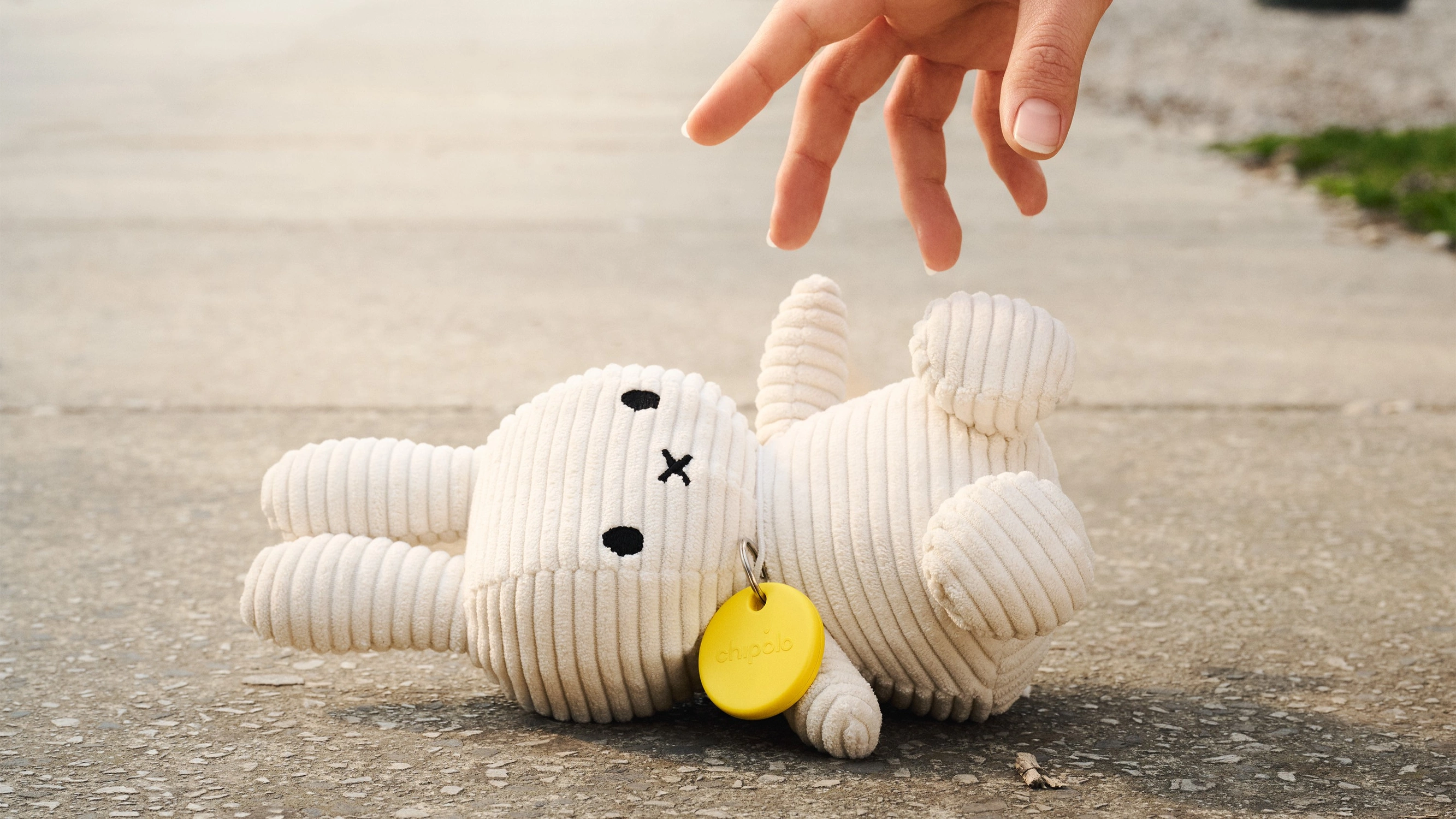 Chipolo Pop Tracker ist an Kuscheltier auf der Straße befestigt