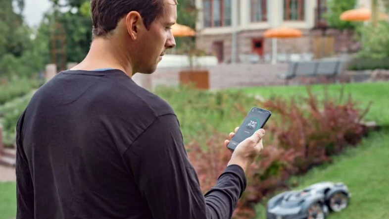 Mann bedient Husqvarna Automower mit Husqvarna Connect Smartphone-App