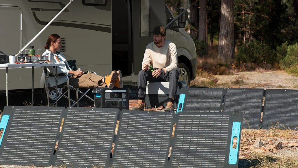 Paar sitzt vor Wohnwagen mit Anker SOLIX mobilen Solarpanelen