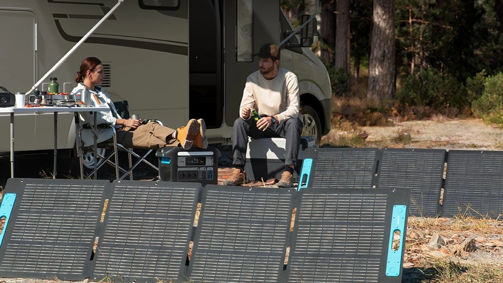 Paar sitzt vor Wohnwagen mit Anker SOLIX mobilen Solarpanelen