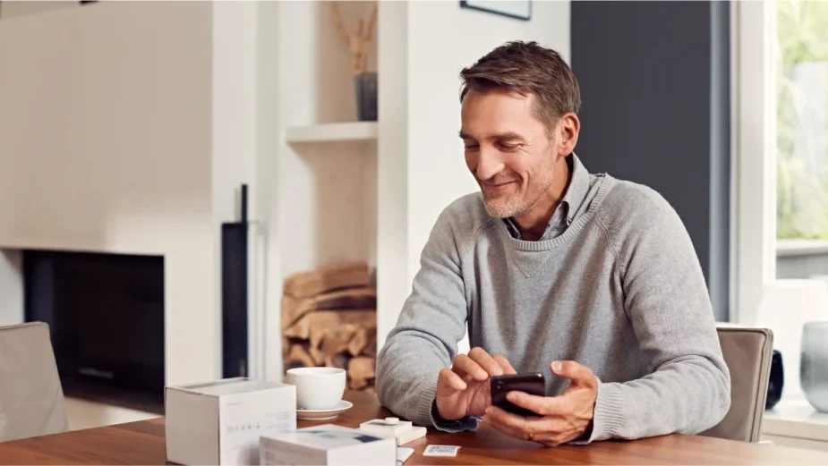Mann sitzt am Tisch und richtet Homematic IP Geräte mit dem Smartphone ein