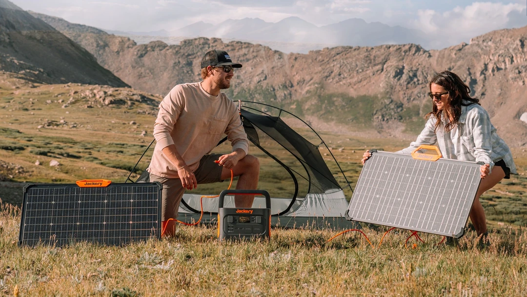 Paar baut beim Camping mobile Solarpanele auf