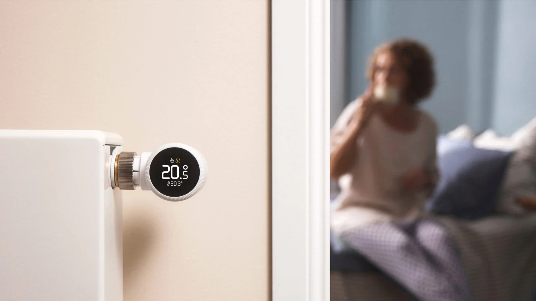 tado° smartes Heizkörperthermostat an Heizung mit Frau im Hintergrund