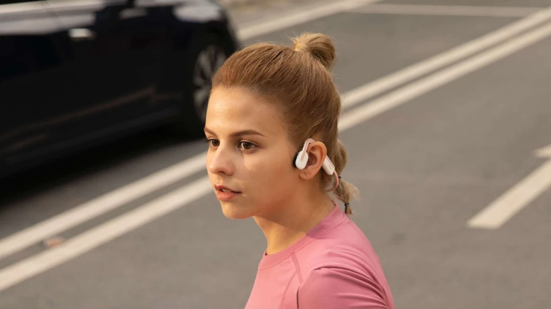 Frau trägt Open-Ear-Kopfhörer beim Joggen auf der Straße