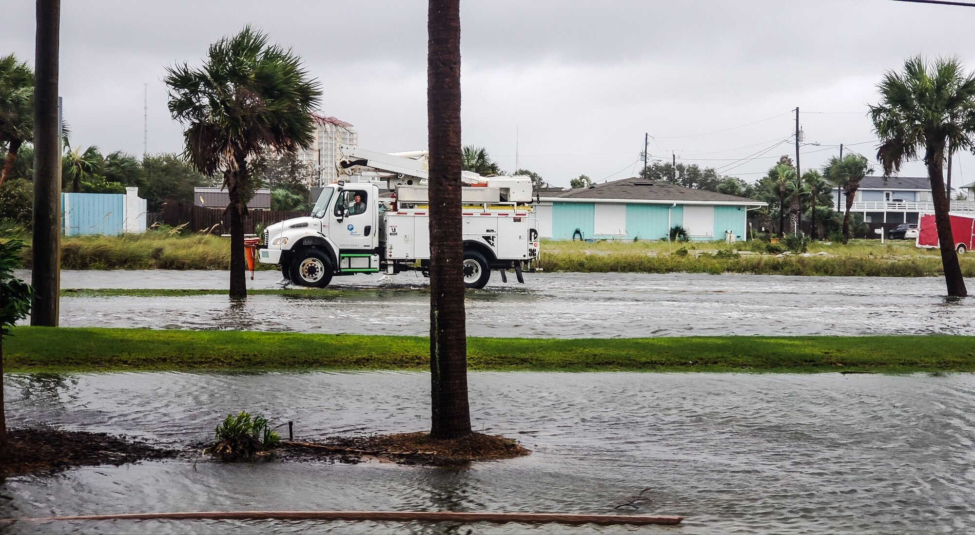 Tuck driving through flooded neighborhood street