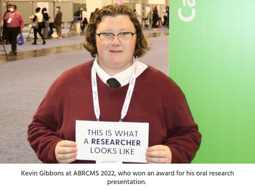 Kevin Gibbons holding a sign that says “This is what a researcher looks like” at ABRCMS 2022