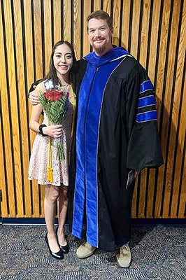 Rebekah and her mentor Charles Spencer, PhD pose together for a photo at graduation. Rebekah is holding flowers.