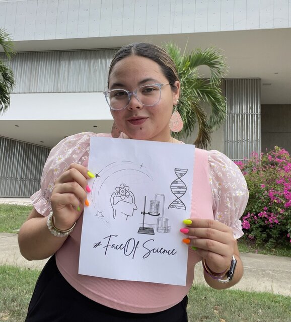 Jorlane De Jesús holding a piece of paper with illustrations of scientific symbols and #FaceOfScience