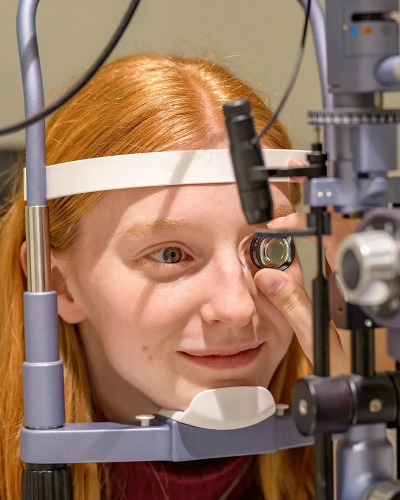 Lachende jongen krijgt een donker rond kindermontuur opgezet door een opticien in de winkel.