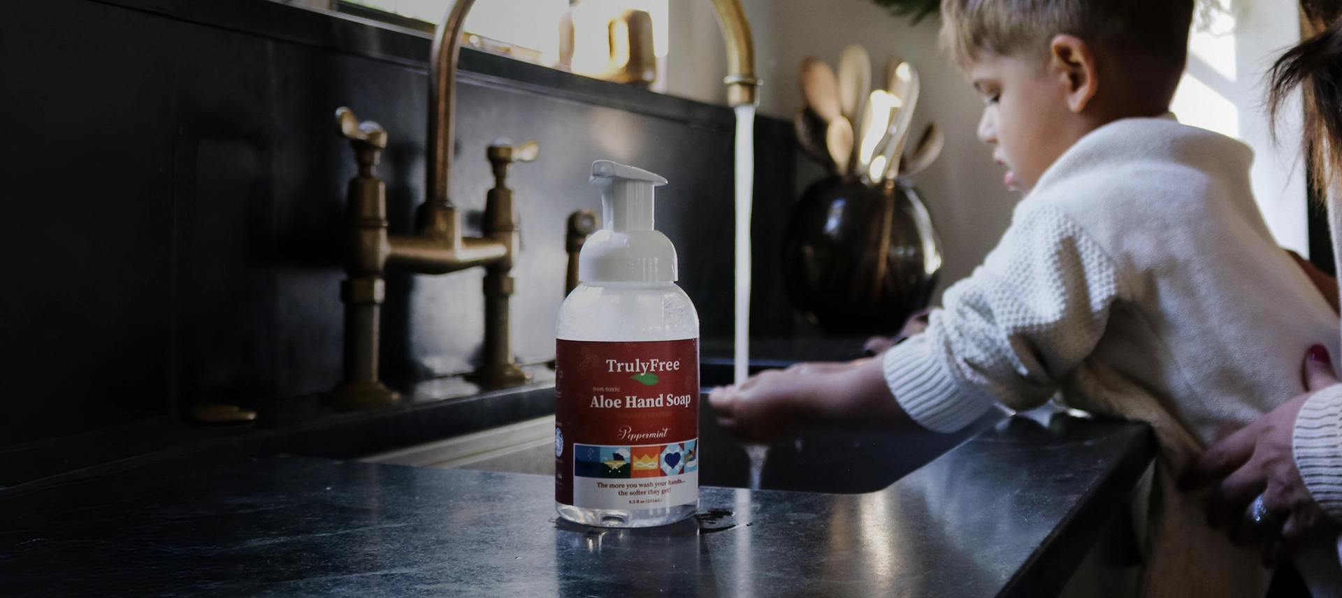 Truly Free Laundry Wash and refill pouch in a laundry room, with a woman and baby in the background.