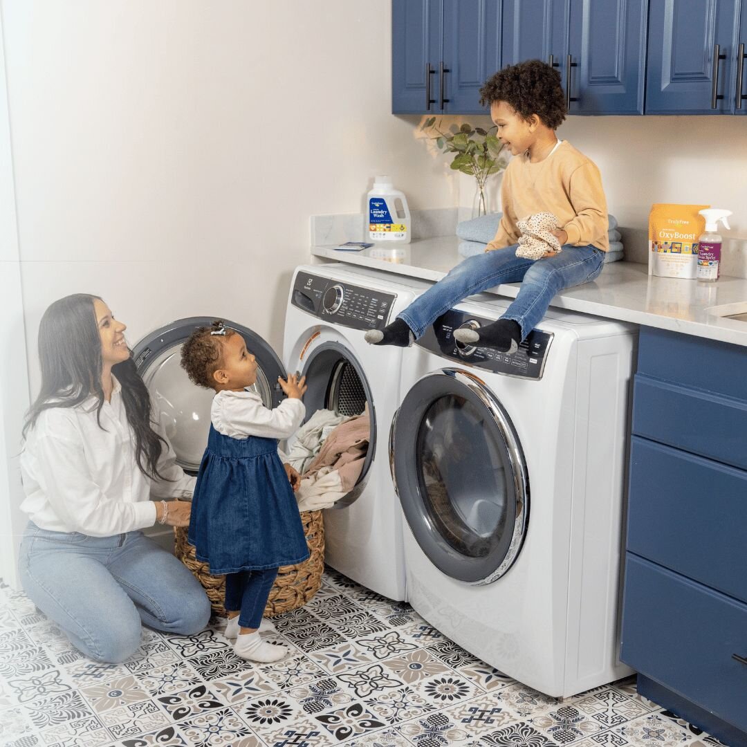 Truly Free Home Laundry Wash and refill pouch in a laundry room, with a woman and baby in the background.