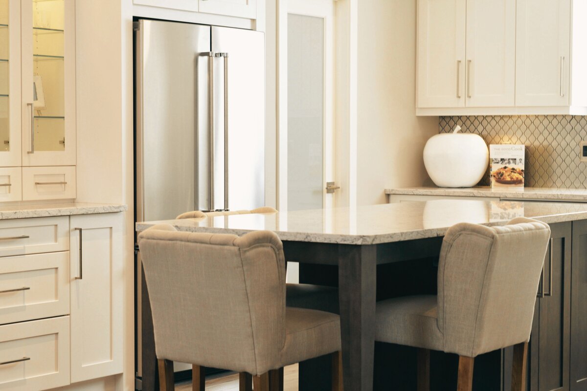 Kitchen counter with chairs and refrigerator in the background