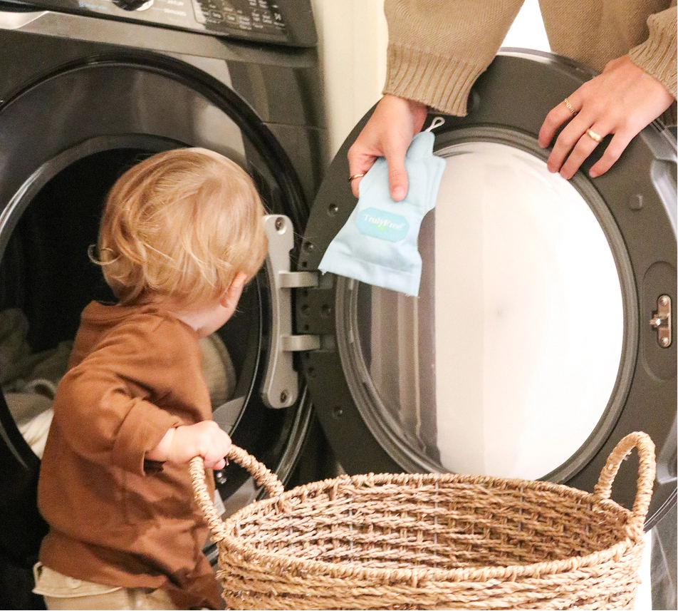 Truly Free Laundry Wash and refill pouch in a laundry room, with a woman and baby in the background.