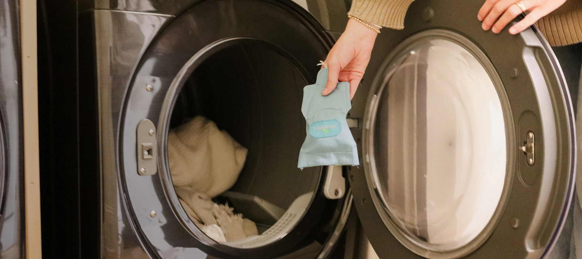 Truly Free Laundry Wash and refill pouch in a laundry room, with a woman and baby in the background.