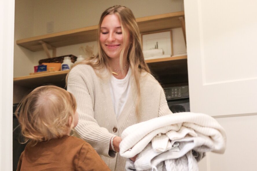 Mom folding laundry with her toddler son.