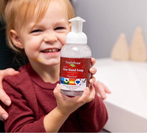 Truly Free Laundry Wash and refill pouch in a laundry room, with a woman and baby in the background.