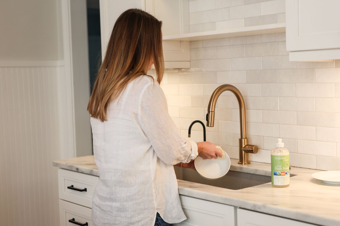 Woman washing dishes with Truly Free Home Non-Toxic Dish Soap