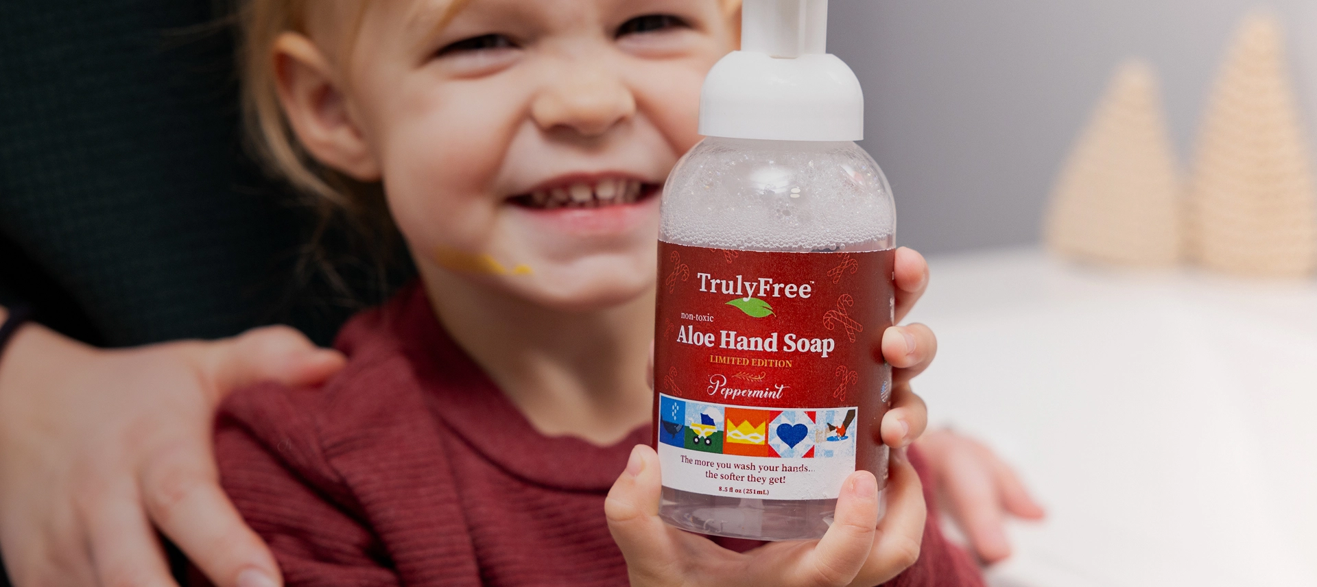 Truly Free Laundry Wash and refill pouch in a laundry room, with a woman and baby in the background.