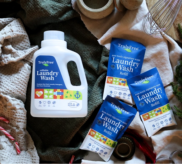 Truly Free Laundry Wash and refill pouch in a laundry room, with a woman and baby in the background.