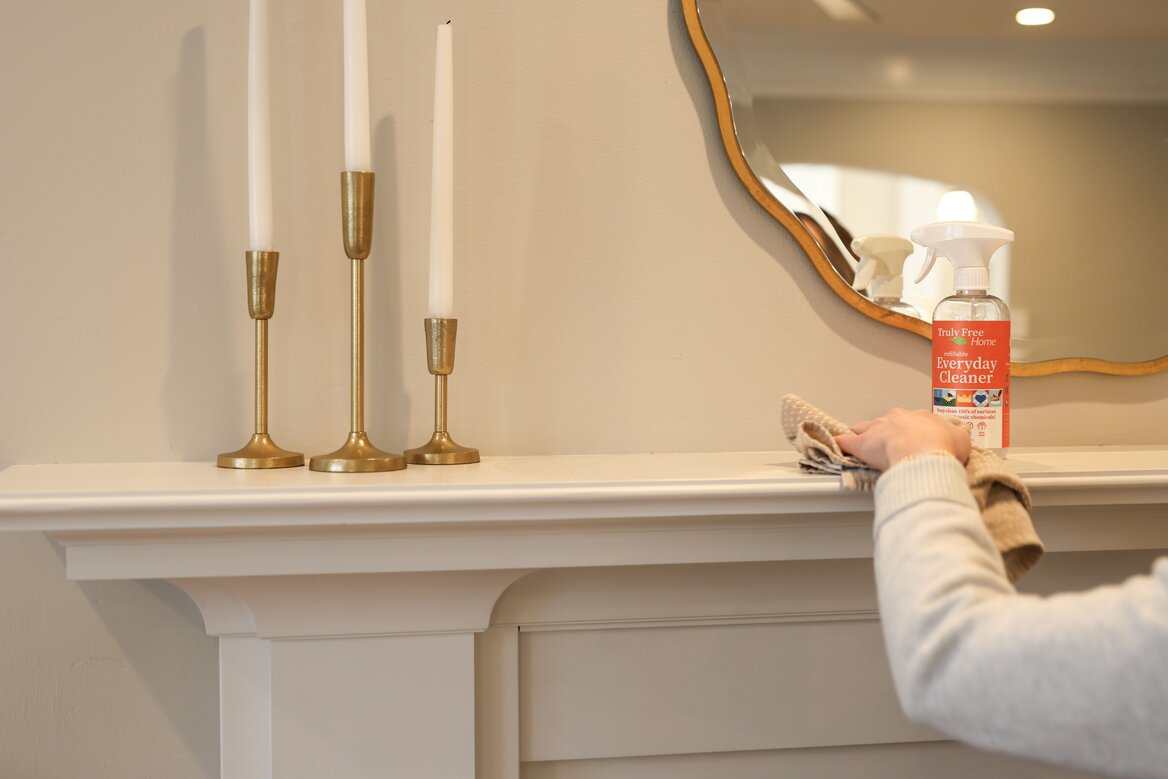 Wiping down a mantle with Truly Free Home Everyday Cleaner
