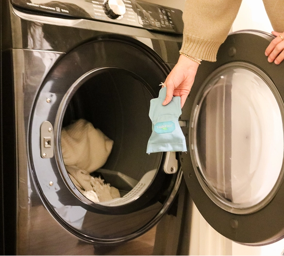 Truly Free Laundry Wash and refill pouch in a laundry room, with a woman and baby in the background.