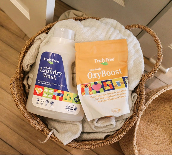 Truly Free Laundry Wash and refill pouch in a laundry room, with a woman and baby in the background.