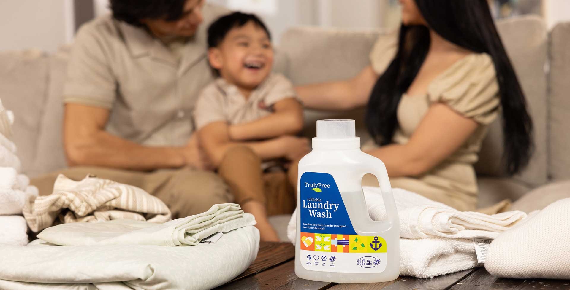 Truly Free Laundry Wash and refill pouch in a laundry room, with a woman and baby in the background.