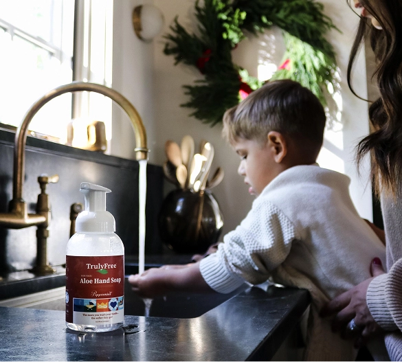 Truly Free Laundry Wash and refill pouch in a laundry room, with a woman and baby in the background.