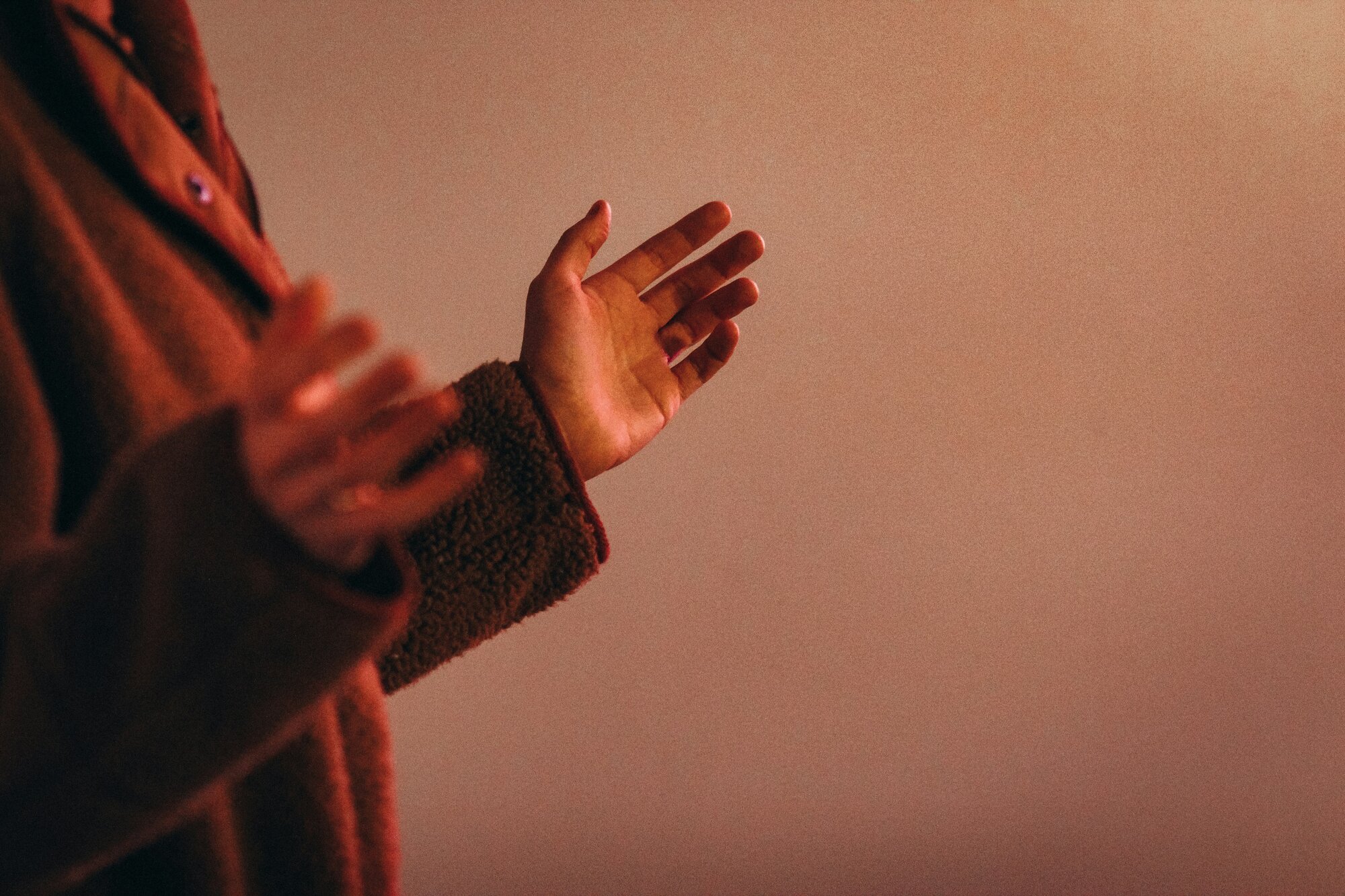 hands held up in orange light