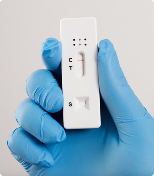 Blue-gloved hand holding a rapid test cassette showing C, T, and S test lines