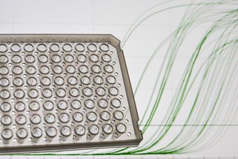 Close-up of a microplate filled with PCR and qPCR master mixes, accompanied by a graphical readout showing qPCR amplification data, highlighting formulations for probe-based assays