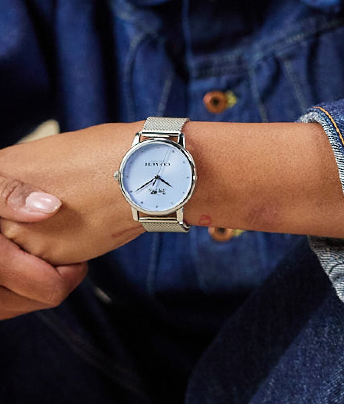 Model wearing coach grand stainless steel mesh bracelet watch with light blue dial